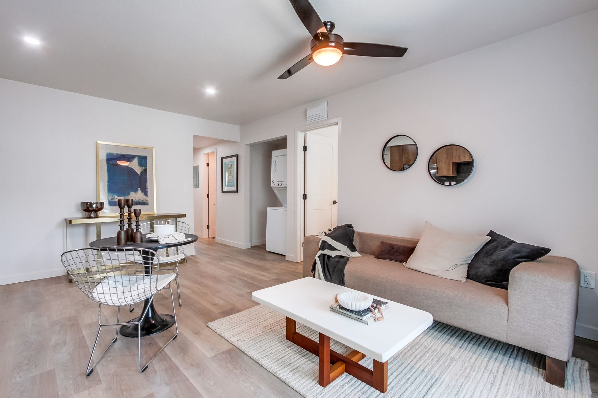 Photo showing a living room area with a washer/dryer area at the entrance to the hallway
