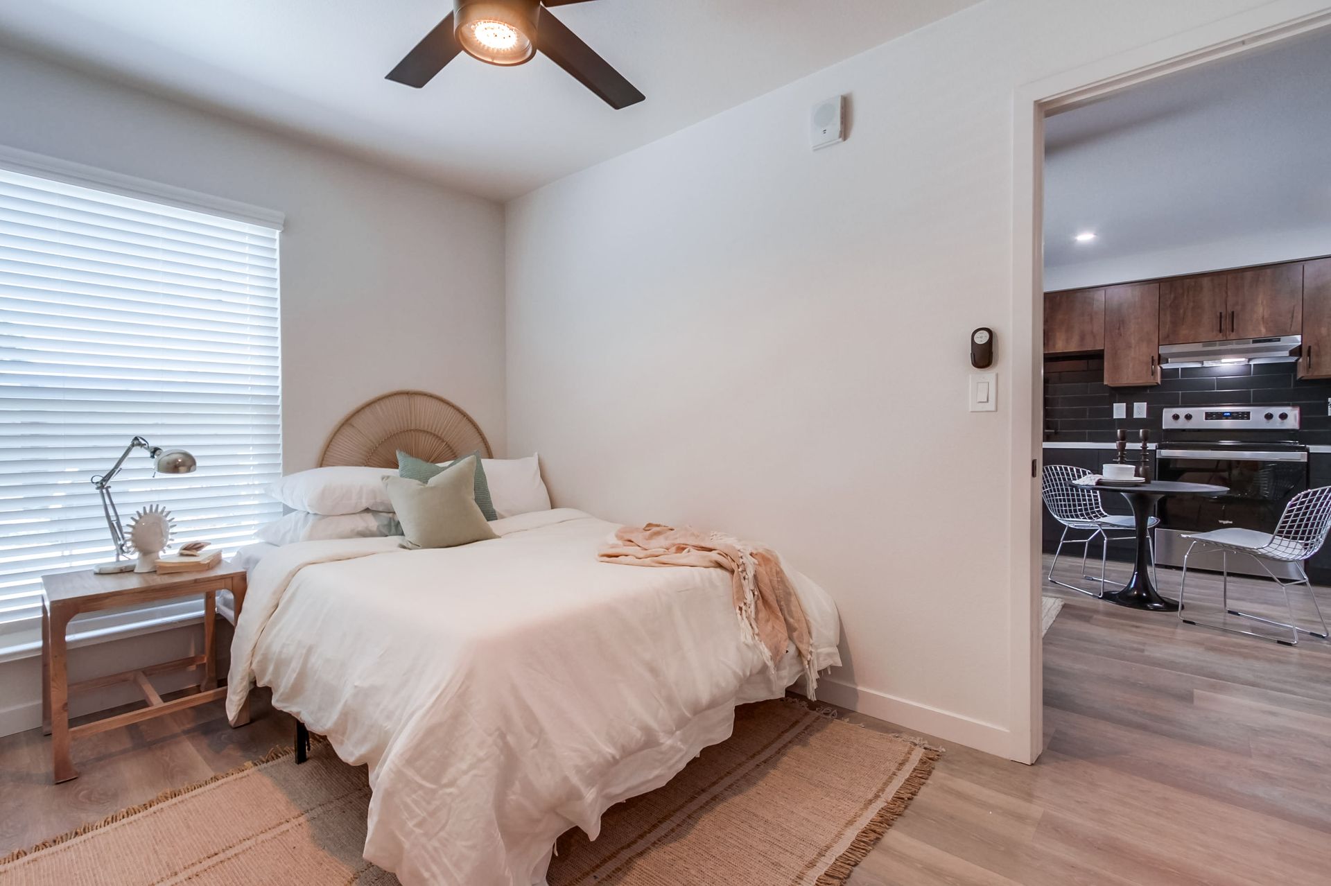 Photo showing a bedroom with the kitchen seen in the background through an open door