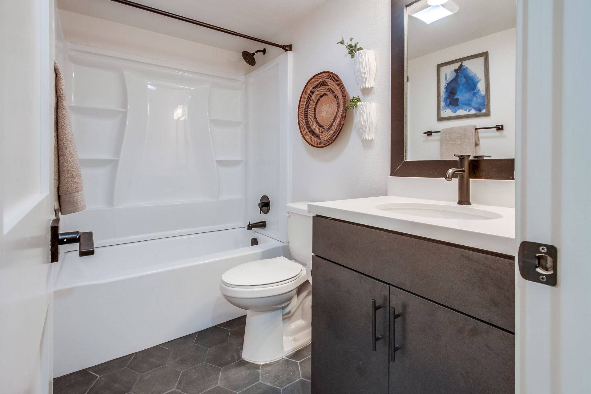 Photo showing a bathroom counter in the foreground, a toilet in the middleground and a shower/tub combo in the background