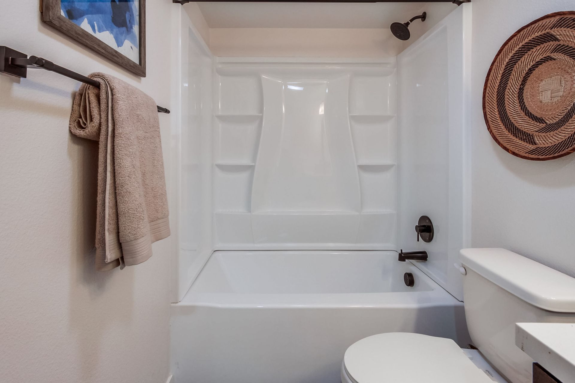 Photo showing a bathtub/shower combo in the background a toilet in the foreground