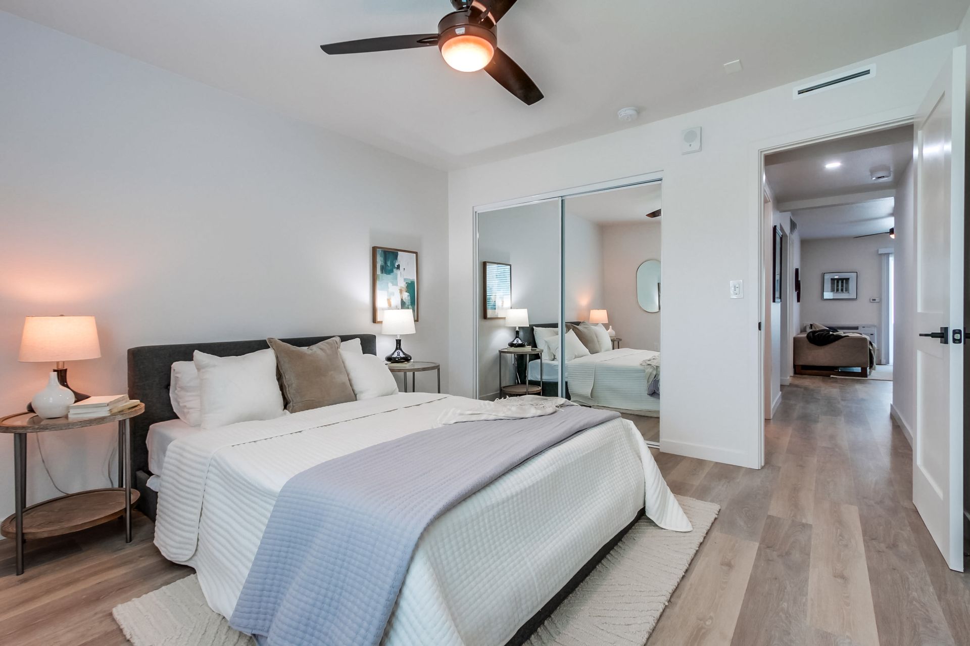 Photo showing a bedroom with the door open and living room in the background