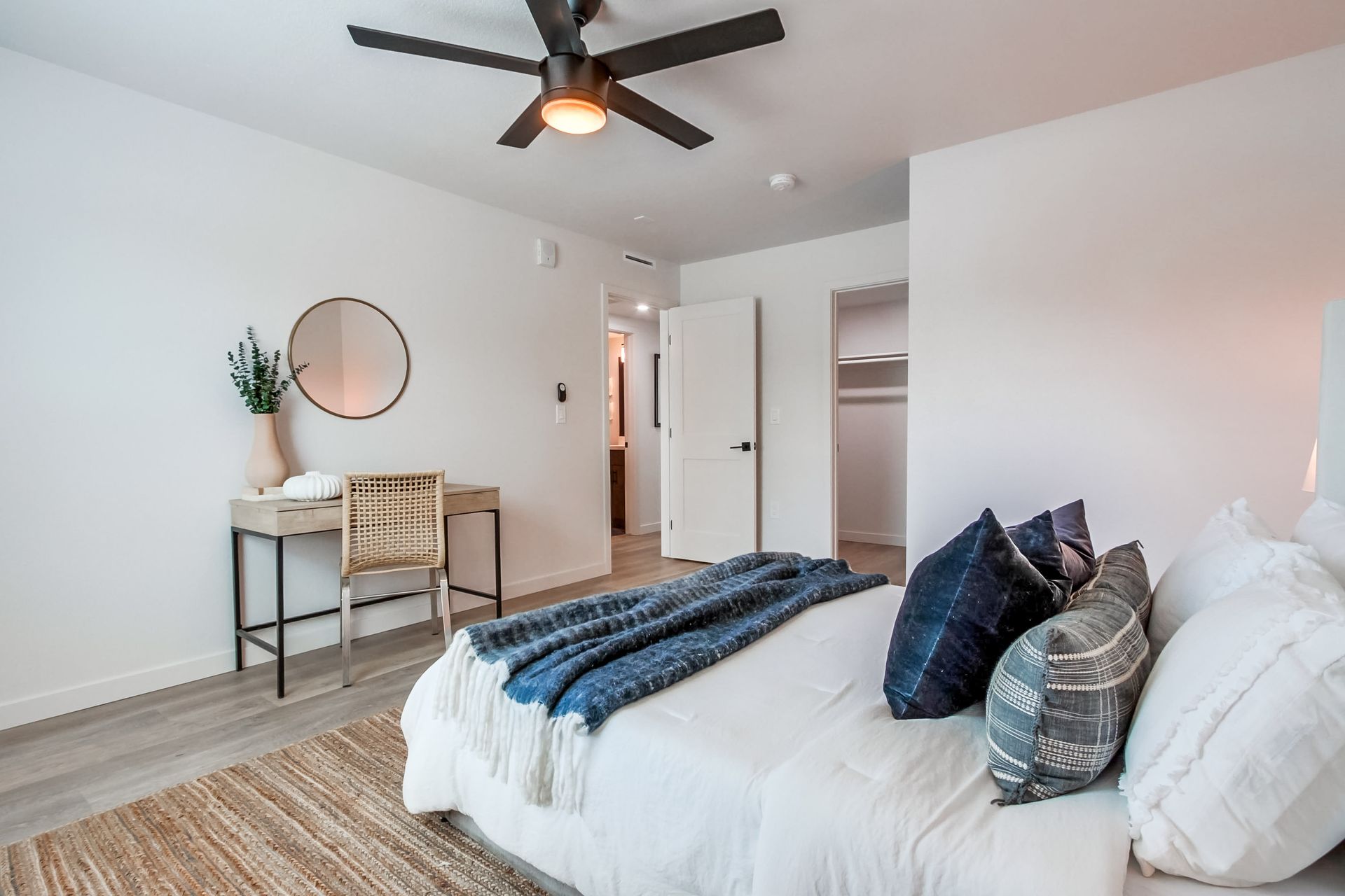 Photo showing a bedroom with a bed against one wall and a desk against another