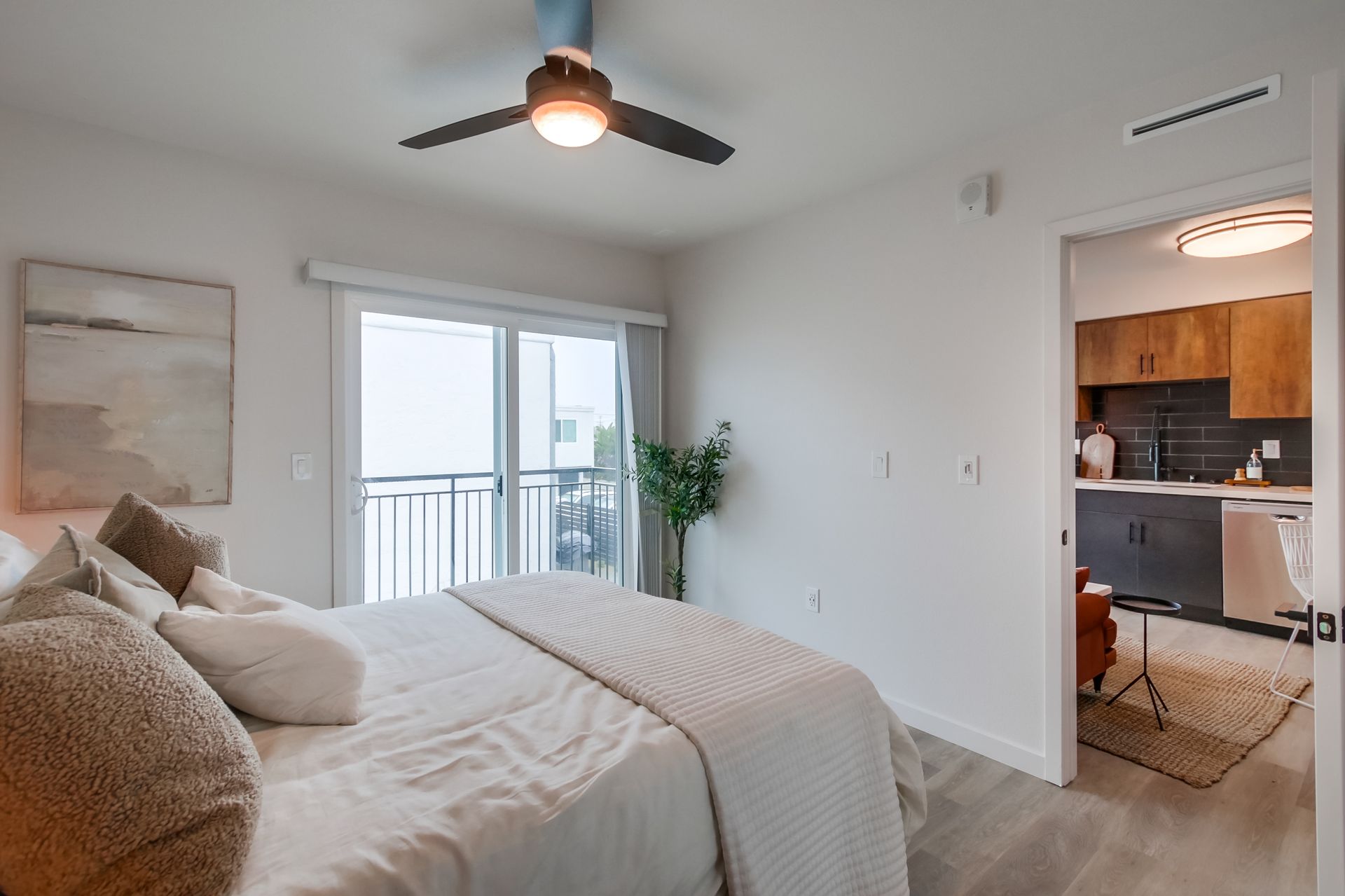 Photo showing a bedroom with the door open and the kitchen in the background