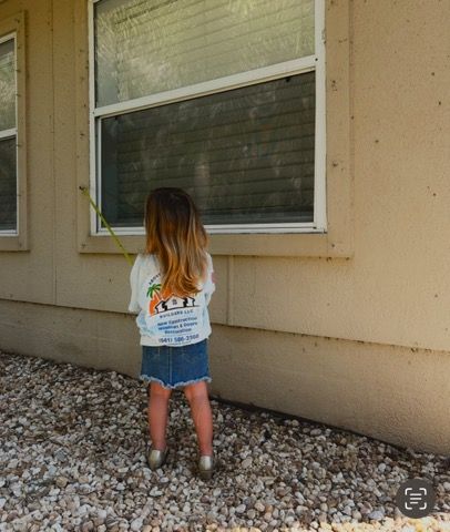 A little girl is measuring a window with a tape measure.