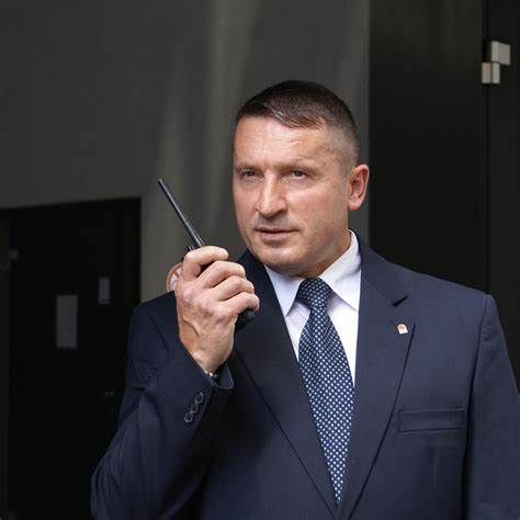 Ein Wachmann im Anzug hält ein Funkgerät in der Hand und wirkt aufmerksam.