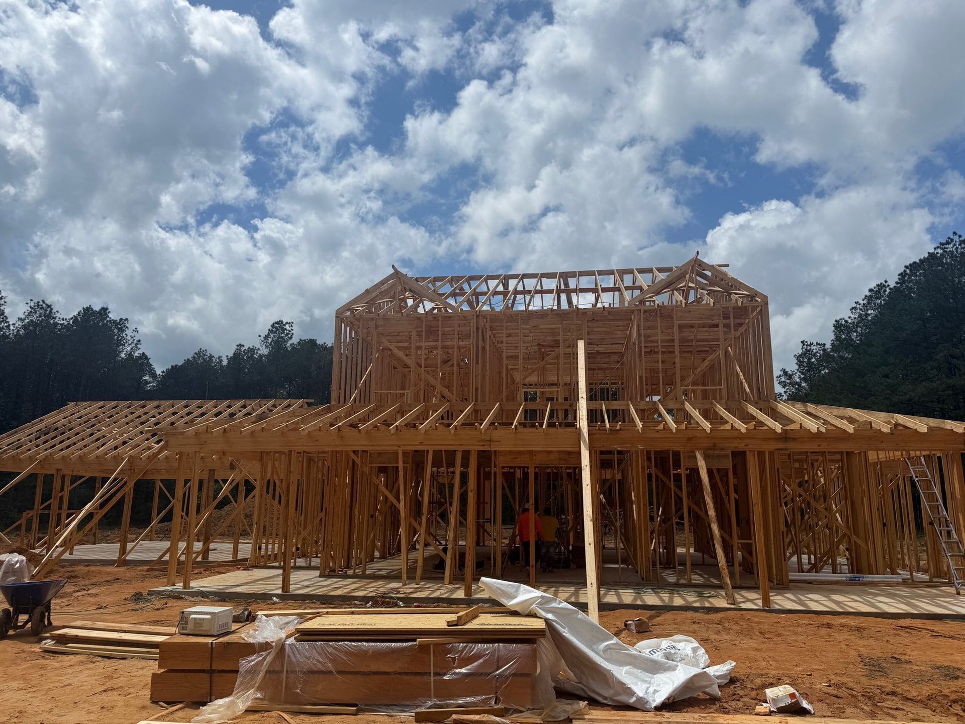Wooden house frame under construction against a cloudy sky.
