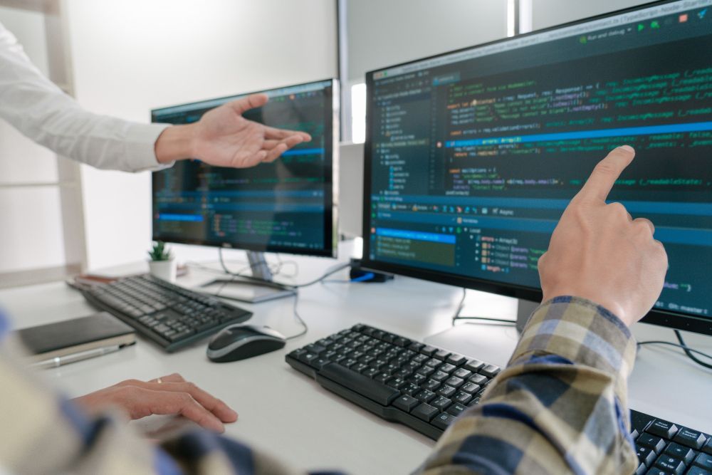 Un hombre señala una pantalla de computadora mientras otro hombre mira.