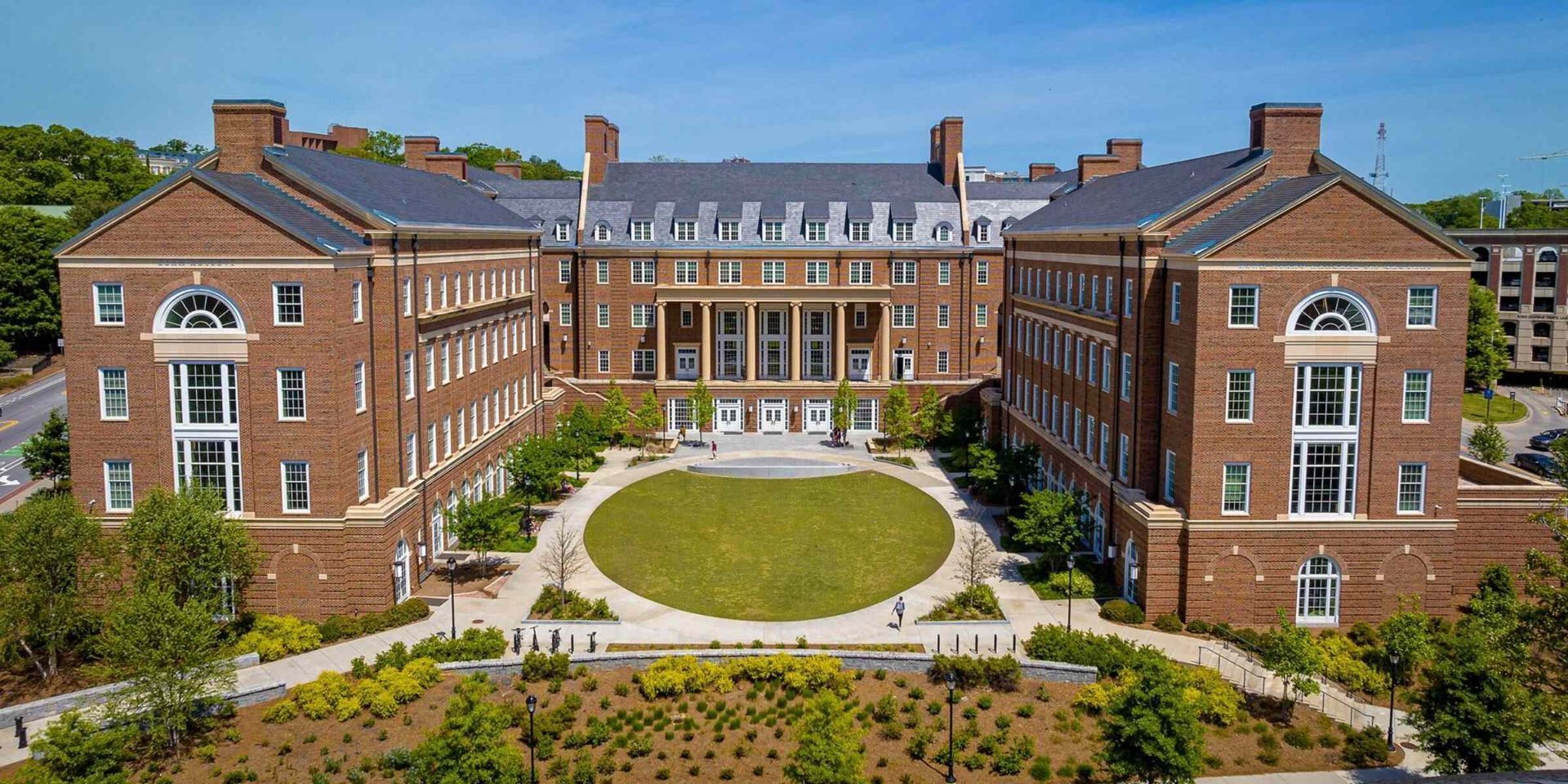 Brick building with a central courtyard and a large lawn.