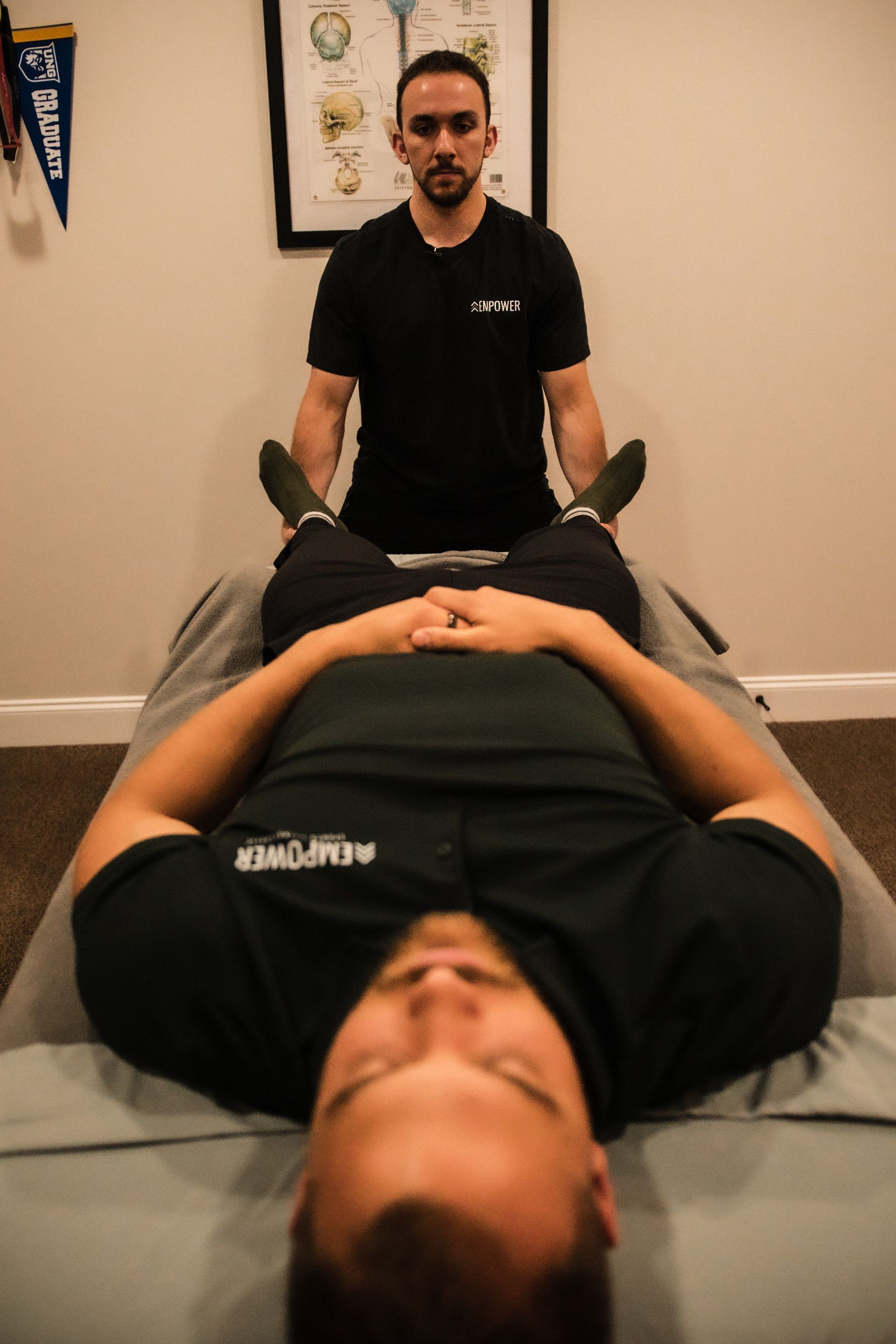 Physiotherapist examines soccer player's ankle injury. Dark room. Gray, white, tan.
