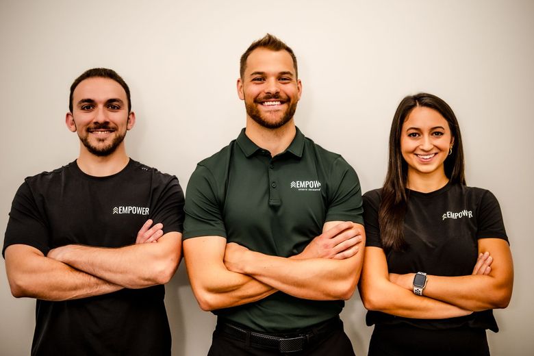 Four people in athletic wear pose inside a modern gym.