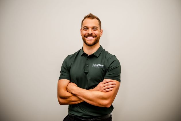 Man with a beard wearing a light gray polo shirt smiling;