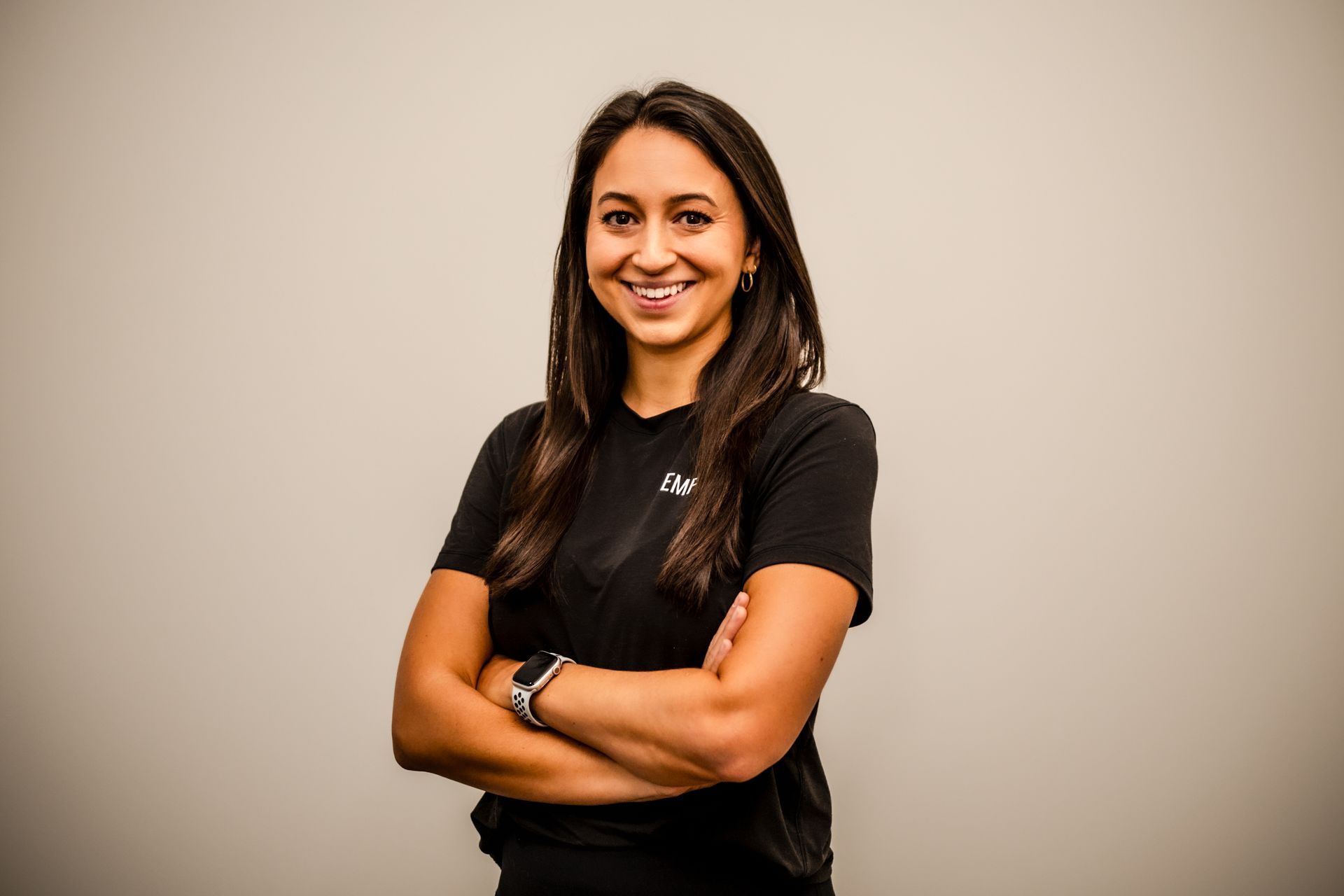 Woman with arms crossed, smiling, wearing a gray
