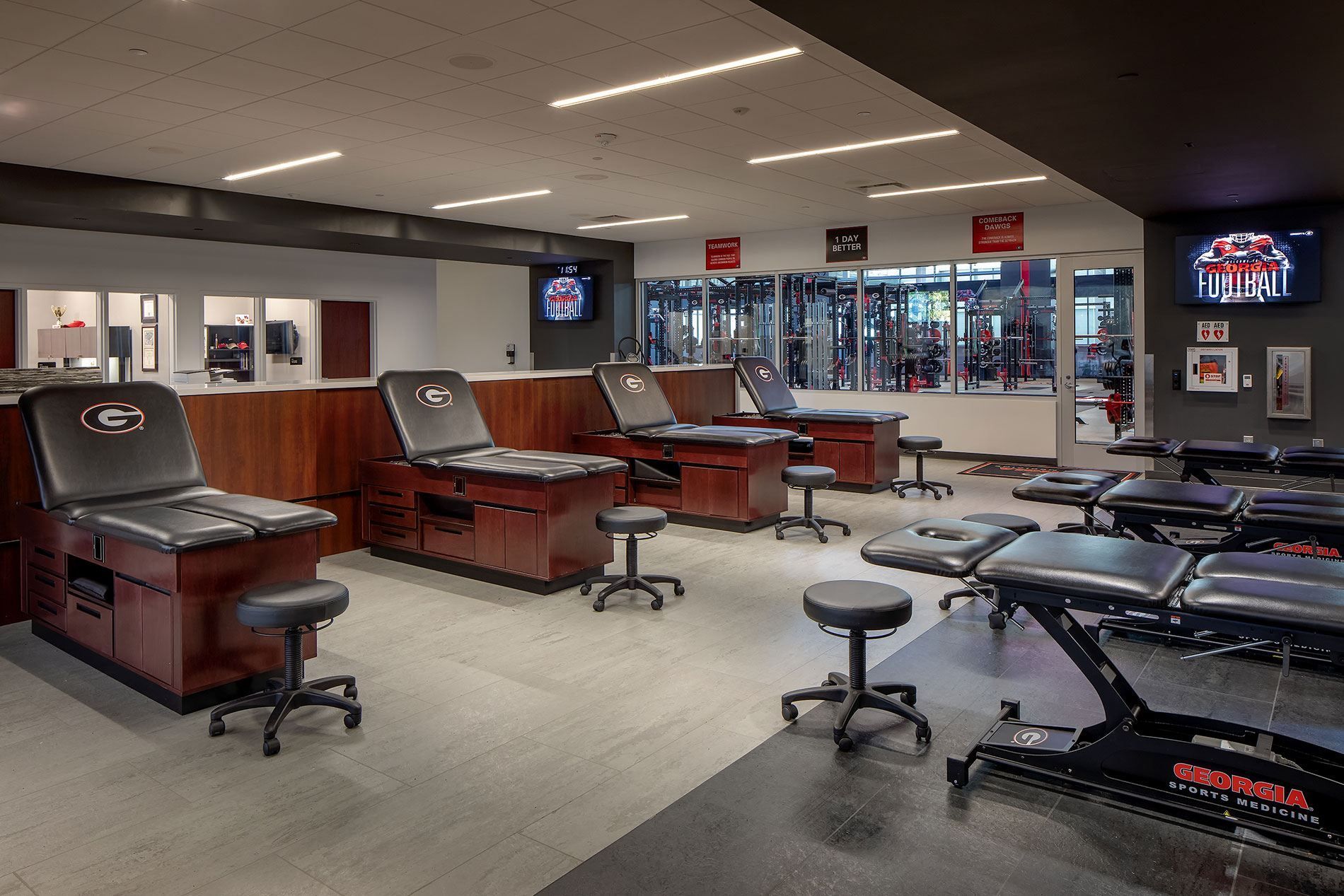 Training room with sports treatment tables and equipment; neutral colors, team logos.