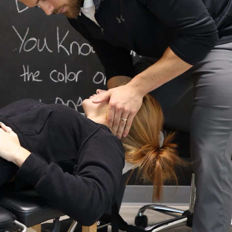 Chiropractor adjusting a woman's neck in a clinic. Woman lies on a table, while the doctor's hands are on her head.