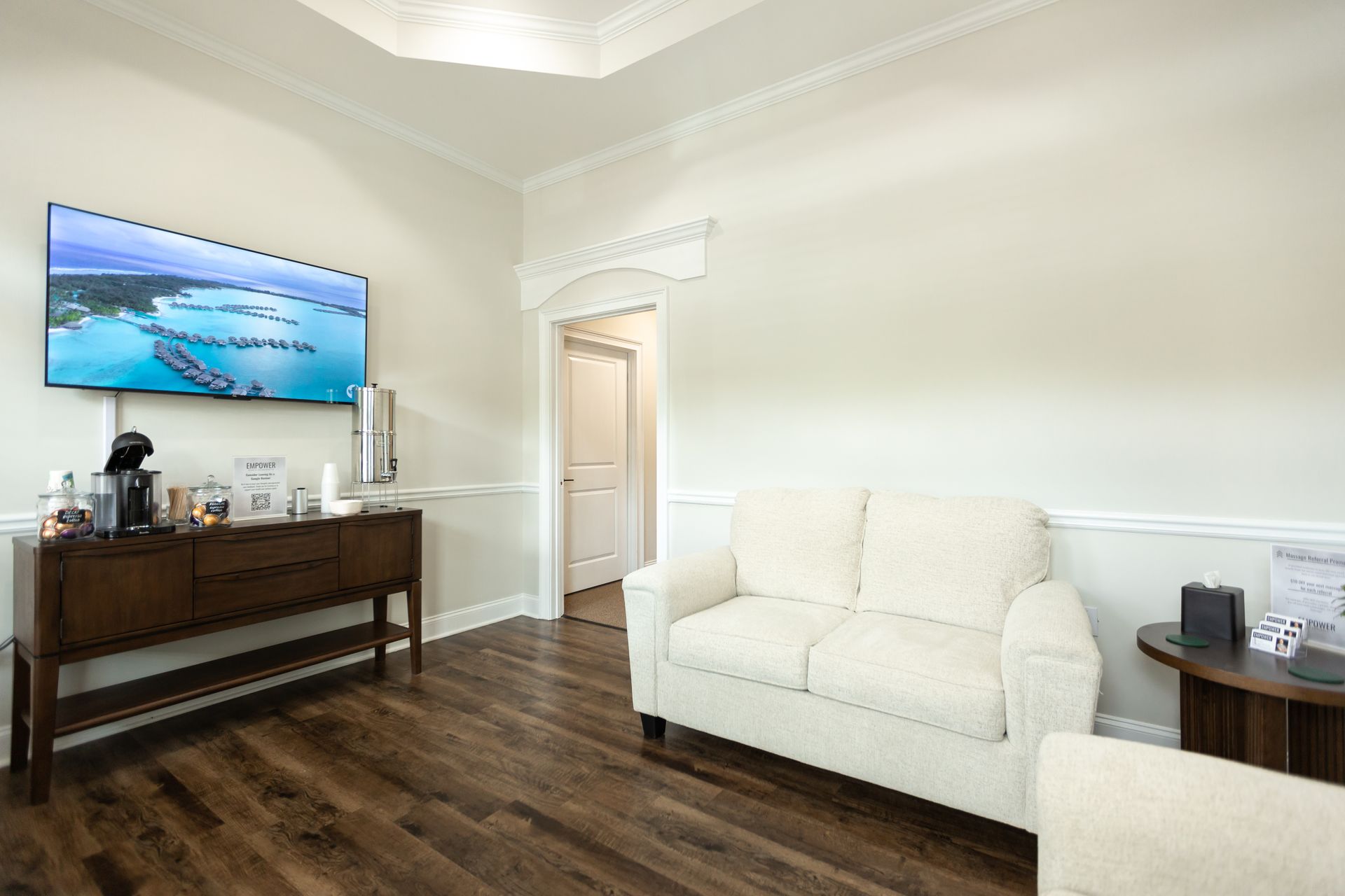 Two armchairs and a small table with a water bottle sit against a white wall with the words