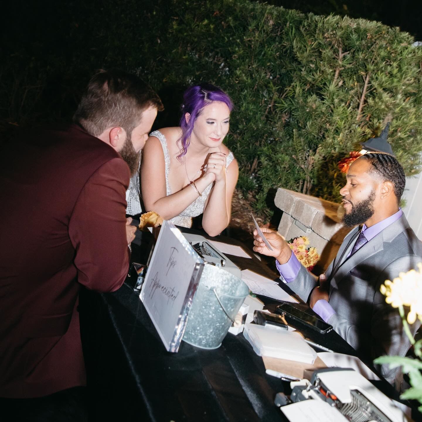 A woman with purple hair is sitting at a table with two men