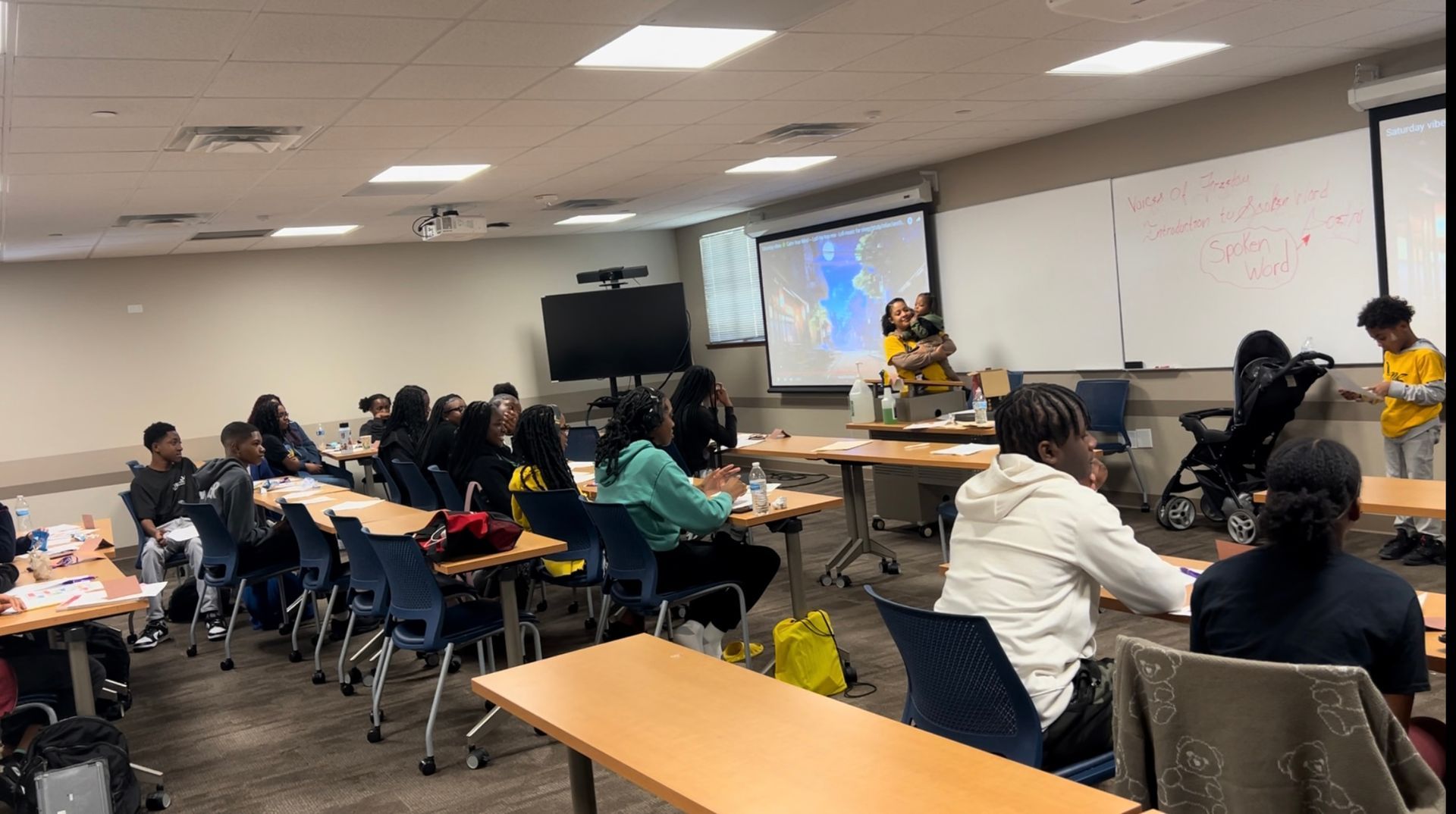 A group of people are sitting at tables in a classroom.
