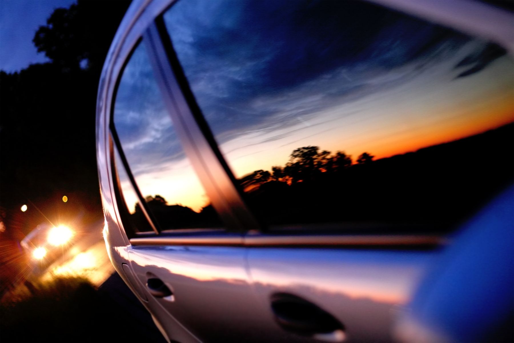 A sunset is reflected in the window of a car