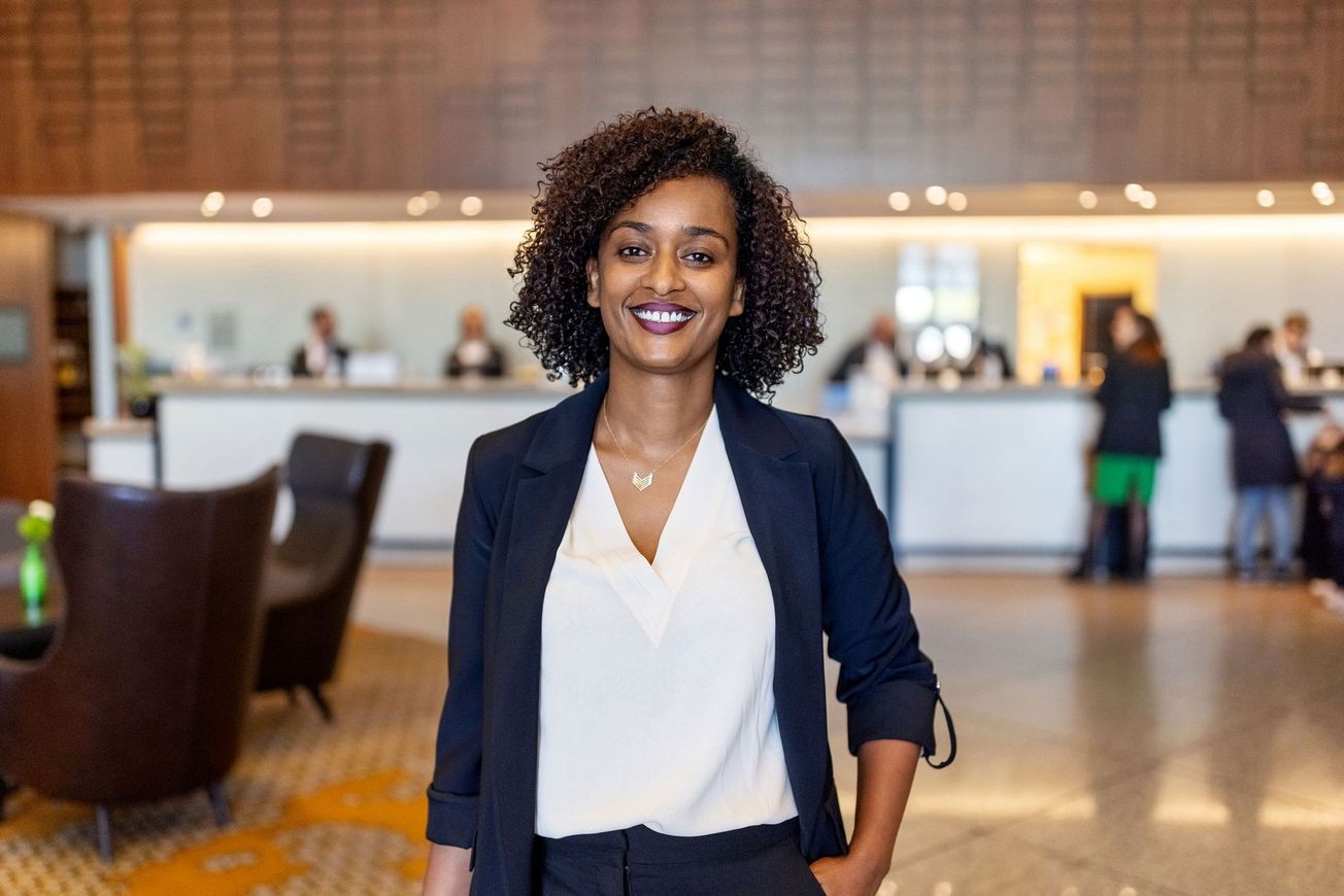 Woman in business attire smiles in a hotel lobby.