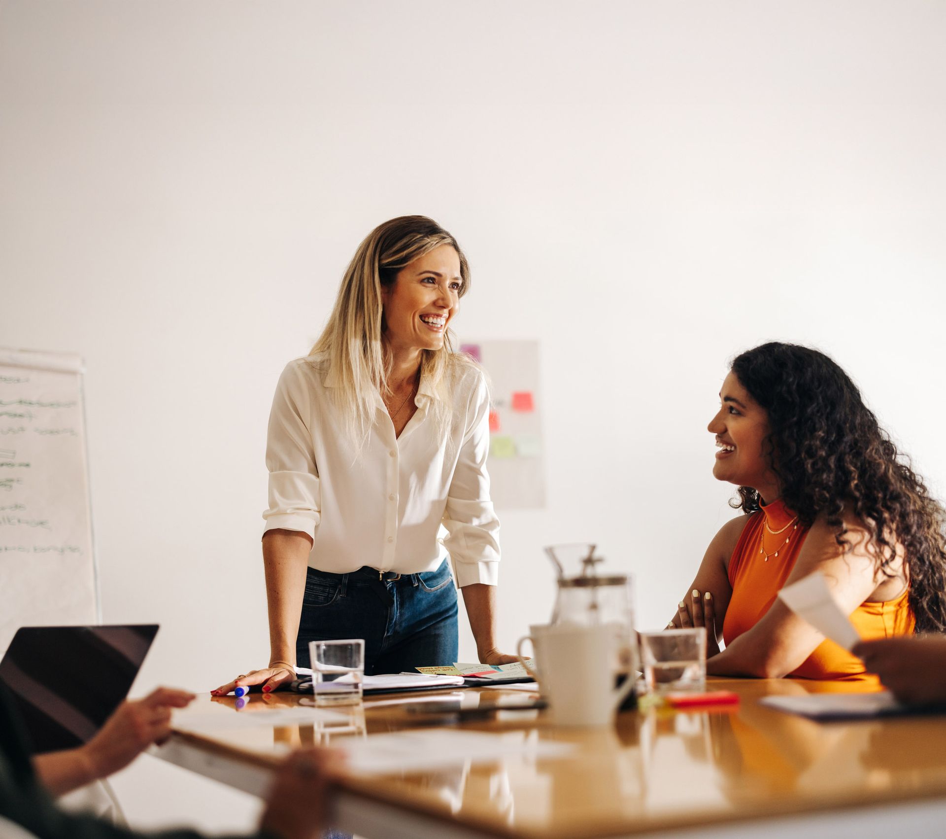 Woman smiles while addressing colleagues at a conference table during a meeting.