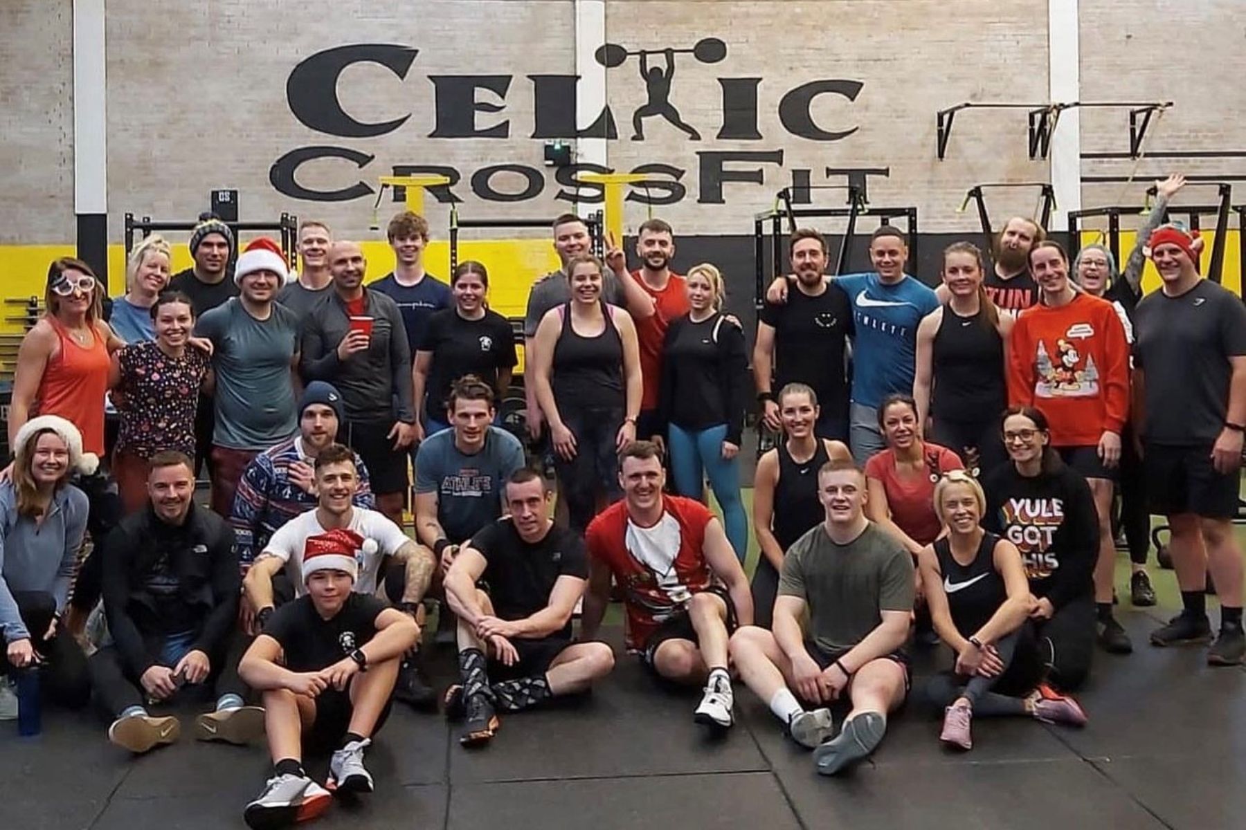 A group of people are posing for a picture in front of a sign that says celtic crossfit