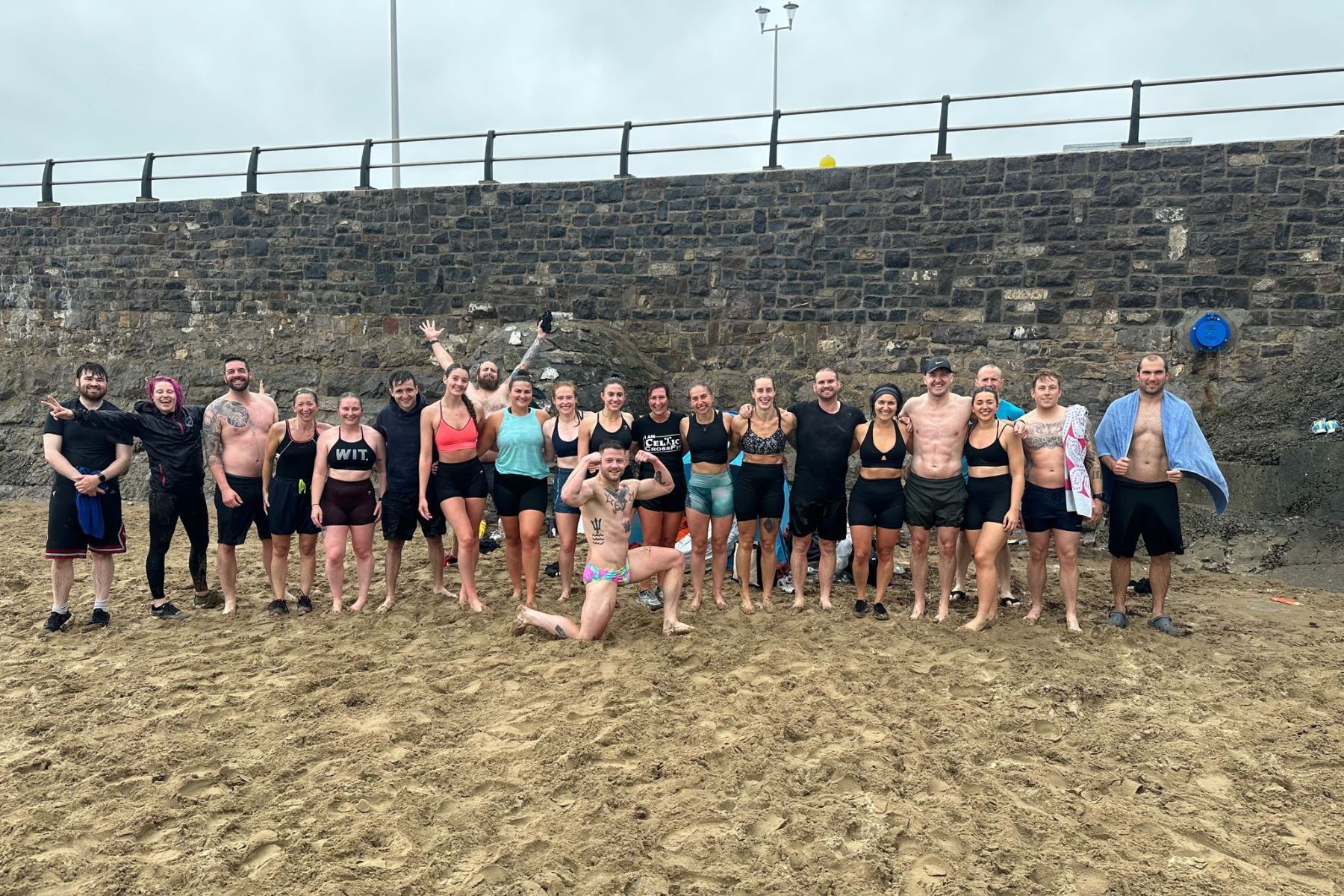 A group of people are posing for a picture on a beach.