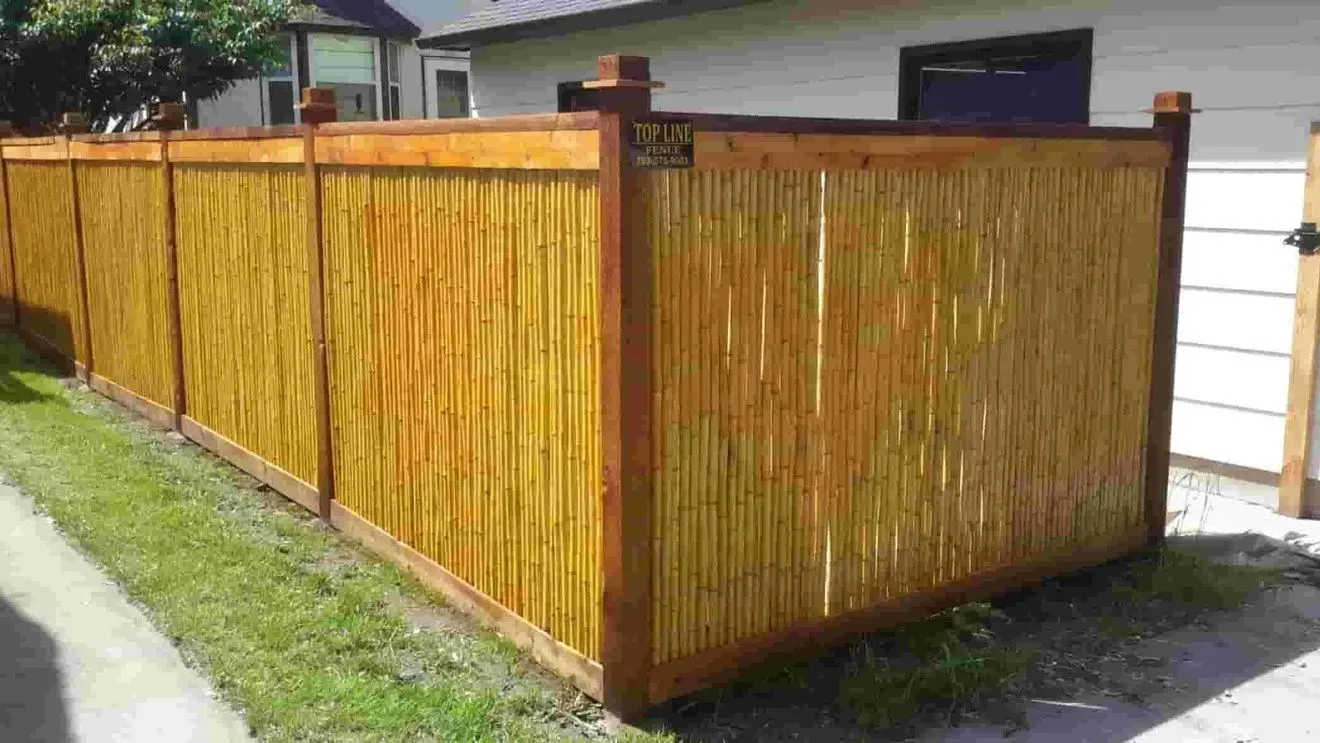 A wooden fence is sitting in the grass in front of a house.