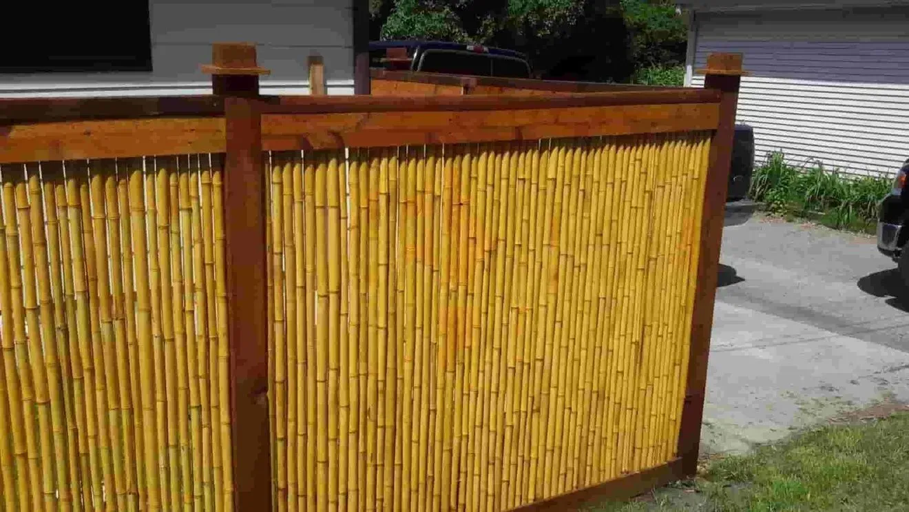 A bamboo fence with a wooden frame is in front of a house.
