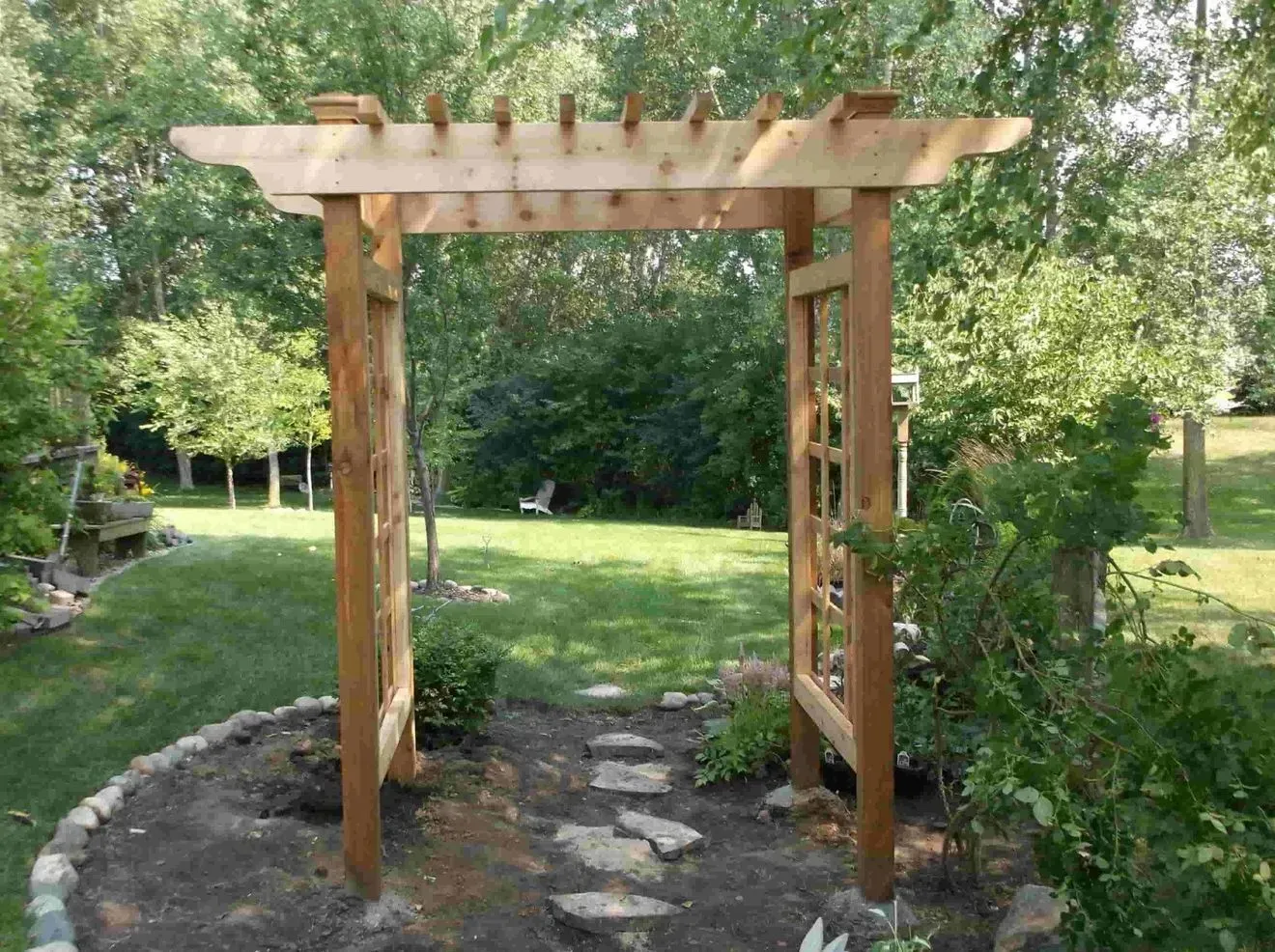 A wooden archway in the middle of a garden
