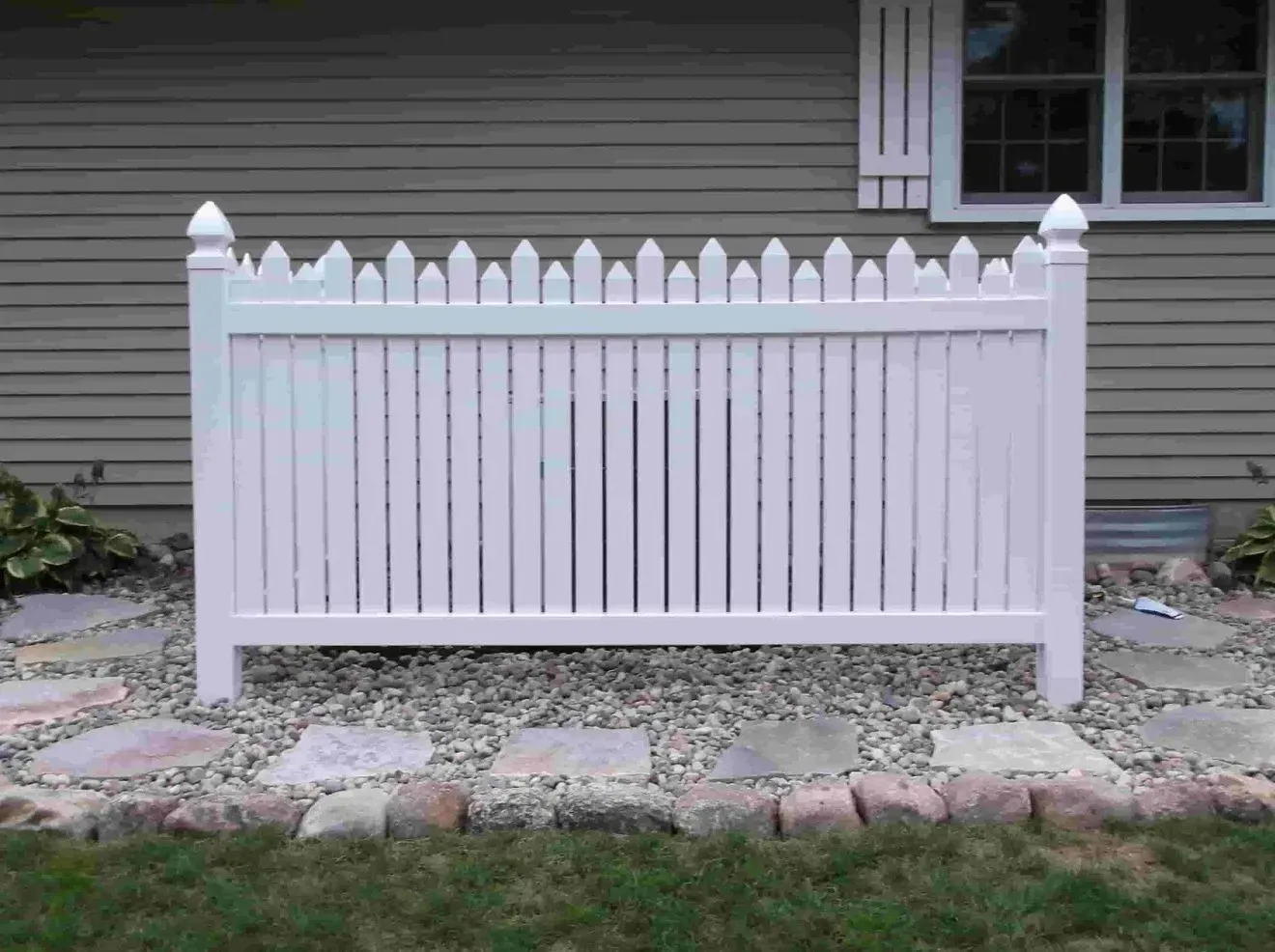 A white picket fence is sitting in front of a house.