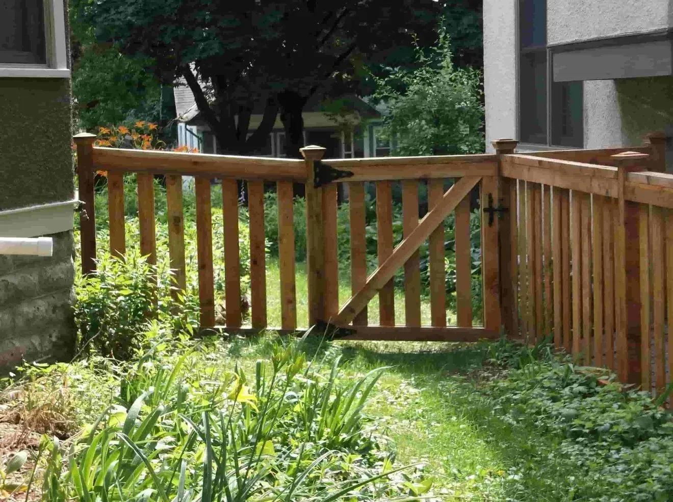 A wooden fence surrounds a lush green yard