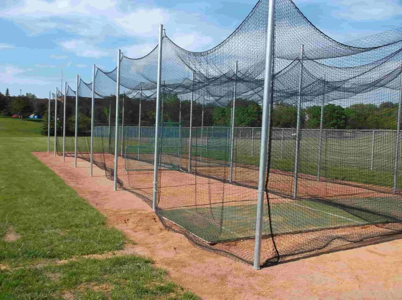 A row of baseball nets sitting on top of a dirt field.