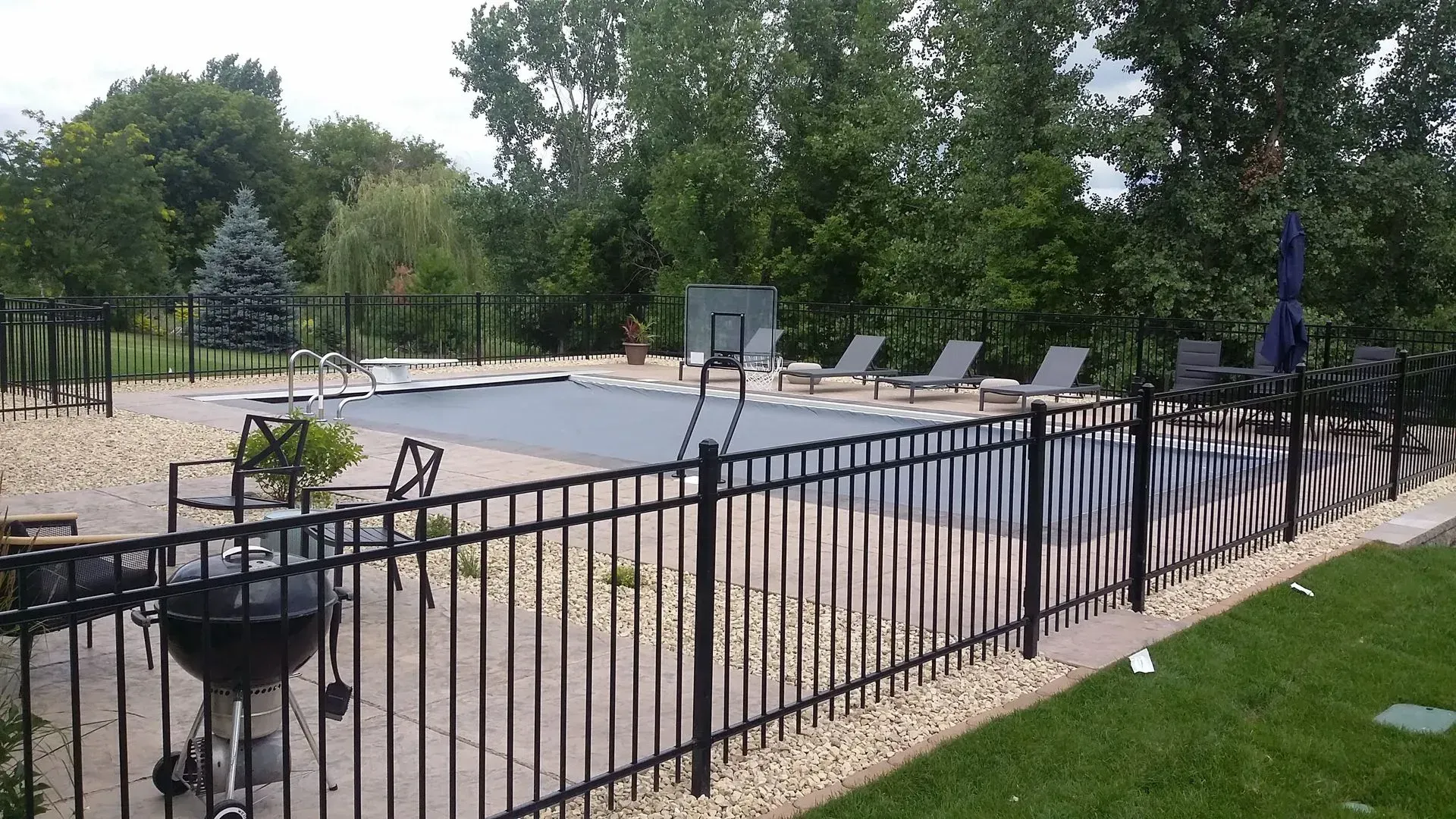 A black fence surrounds a large swimming pool.