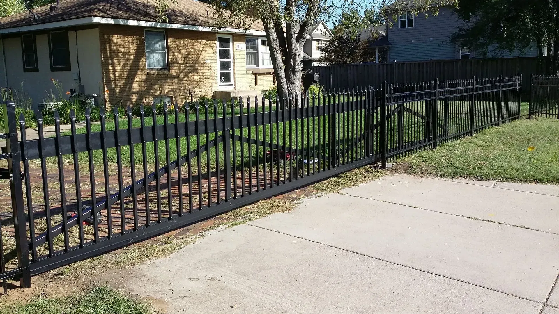 A metal fence surrounds a driveway in front of a house