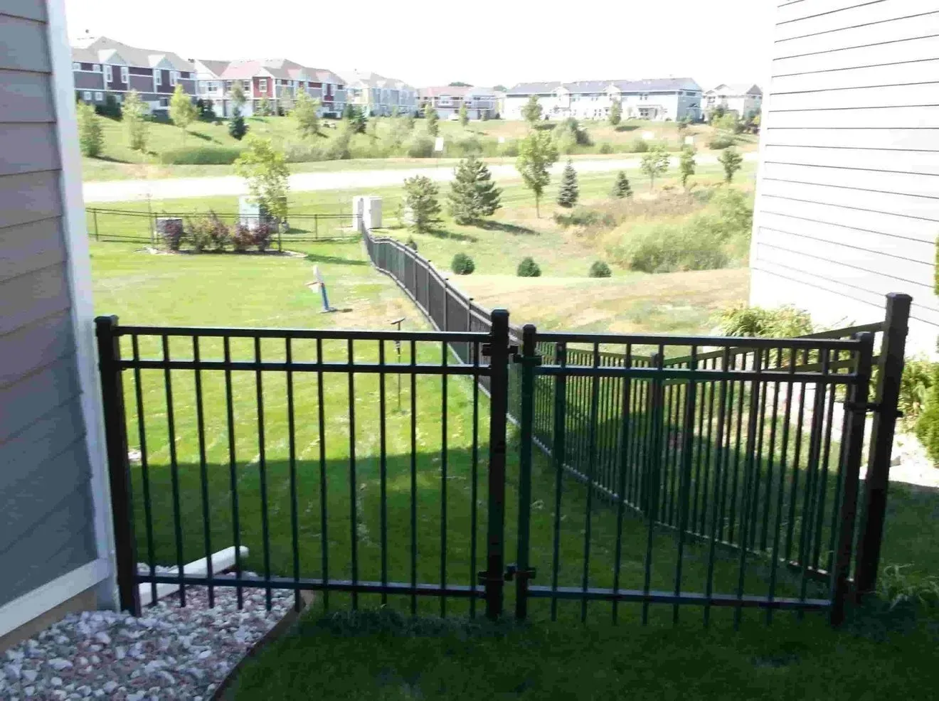 A black metal fence surrounds a lush green yard