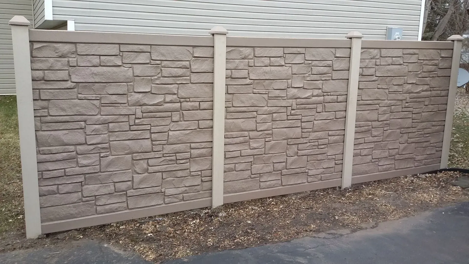 A stone fence with a house in the background