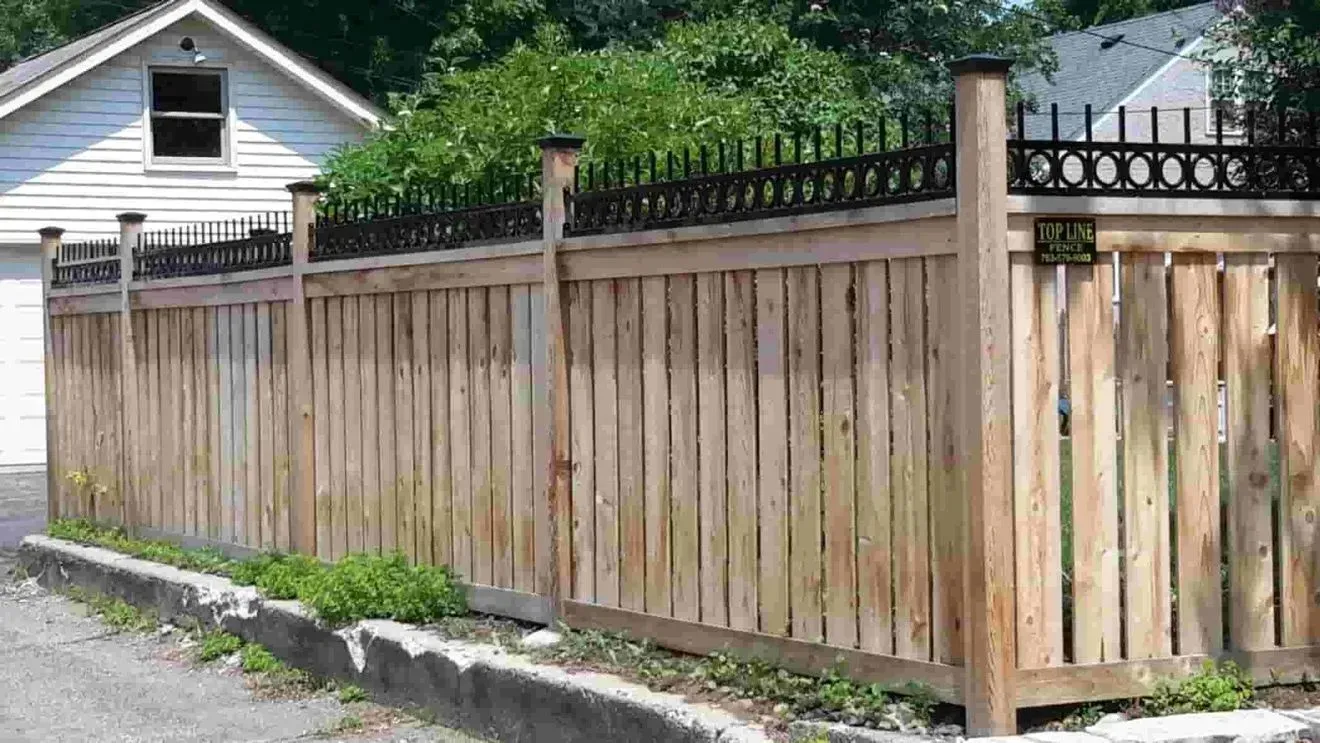 A wooden fence is surrounding a white house.