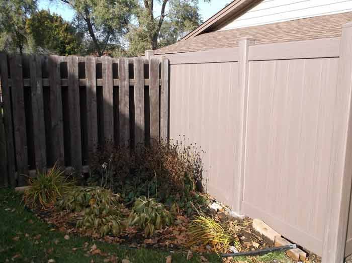 A wooden fence is sitting next to a house in a backyard.
