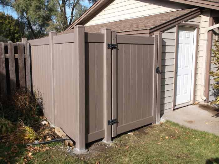 A brown fence with a gate in front of a house.