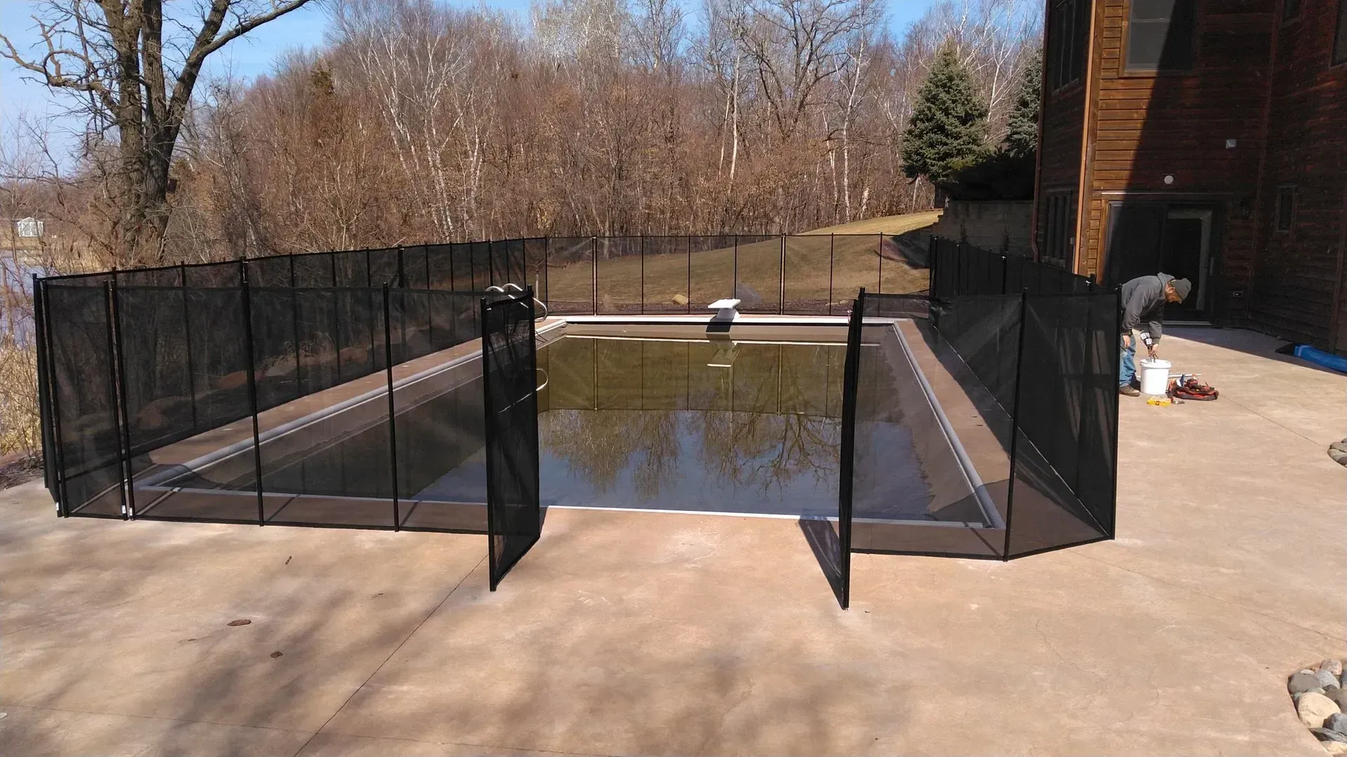 A swimming pool with a fence around it and a house in the background.