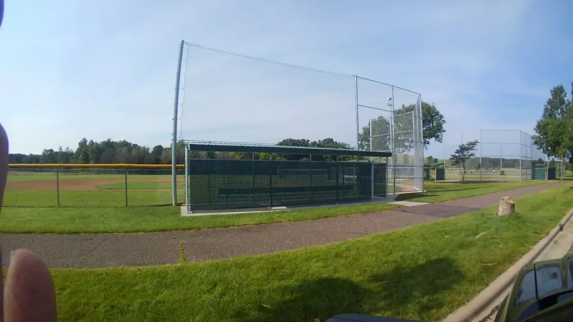 A person is standing in front of a baseball field.