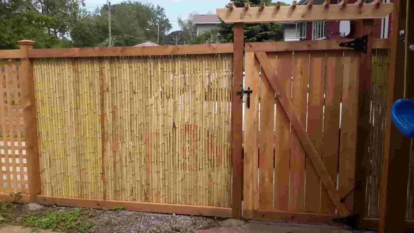 A wooden fence with a gate and a pergola on top of it.