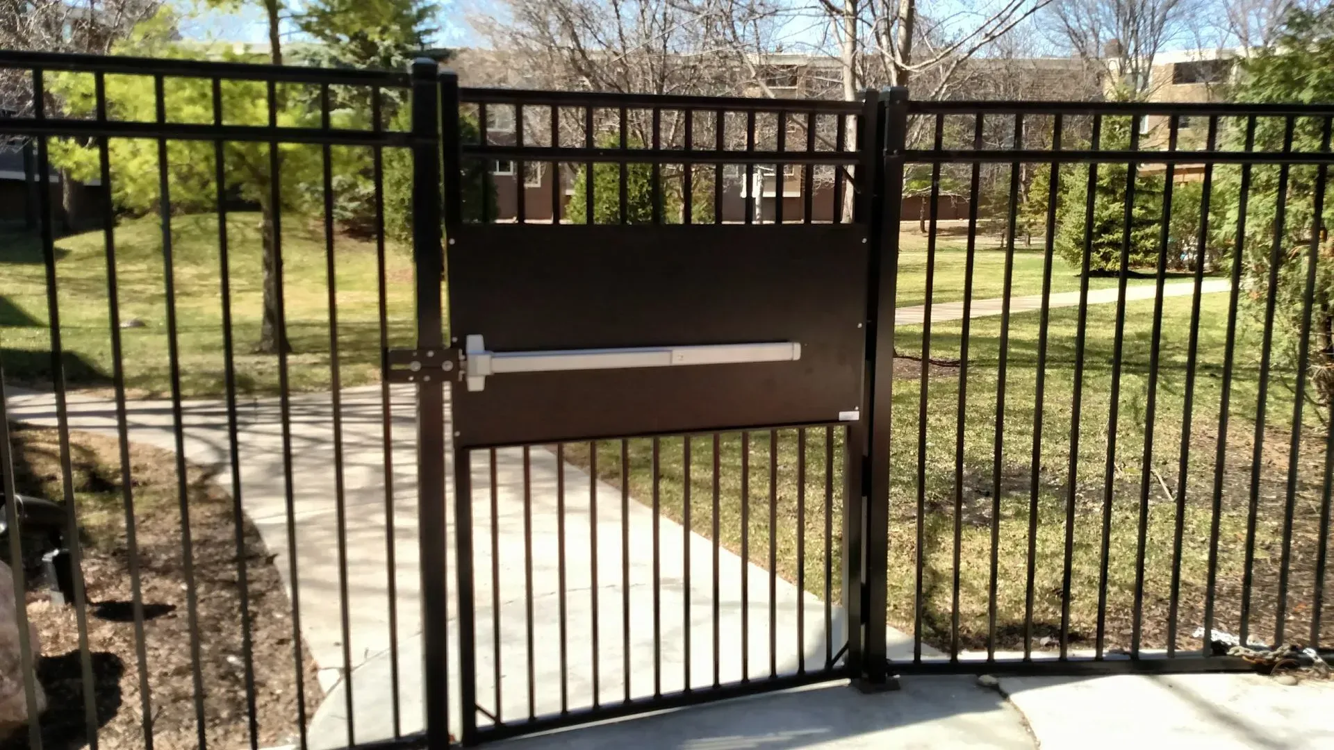 A metal fence with a door in the middle of it.