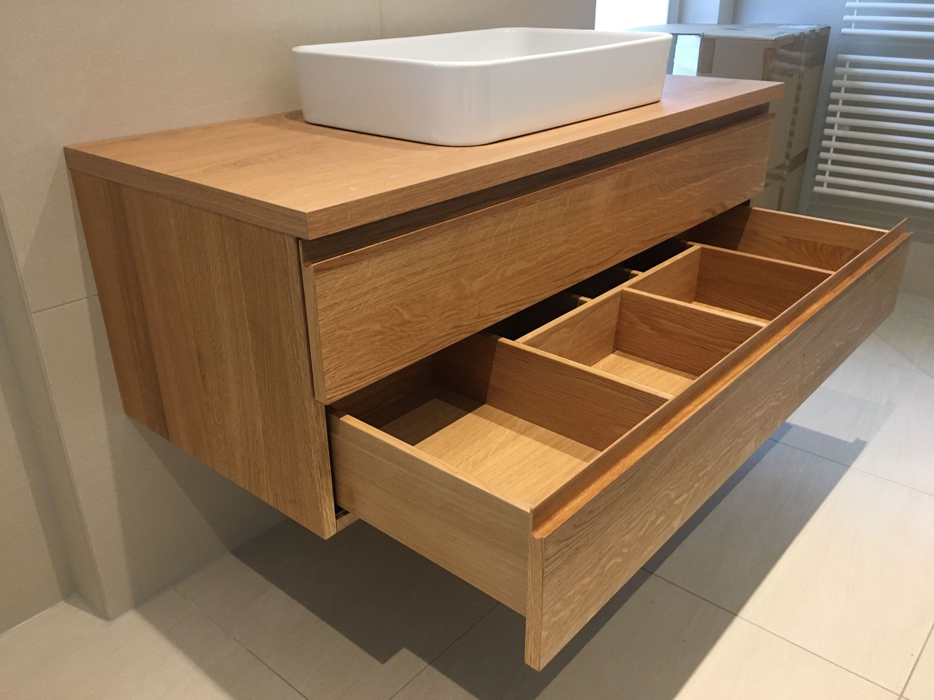 Badmöbel. Waschbecken-Unterschrank in Massivholz Eiche. Schubkasten mit eingfräster Griffleiste geöffnet.