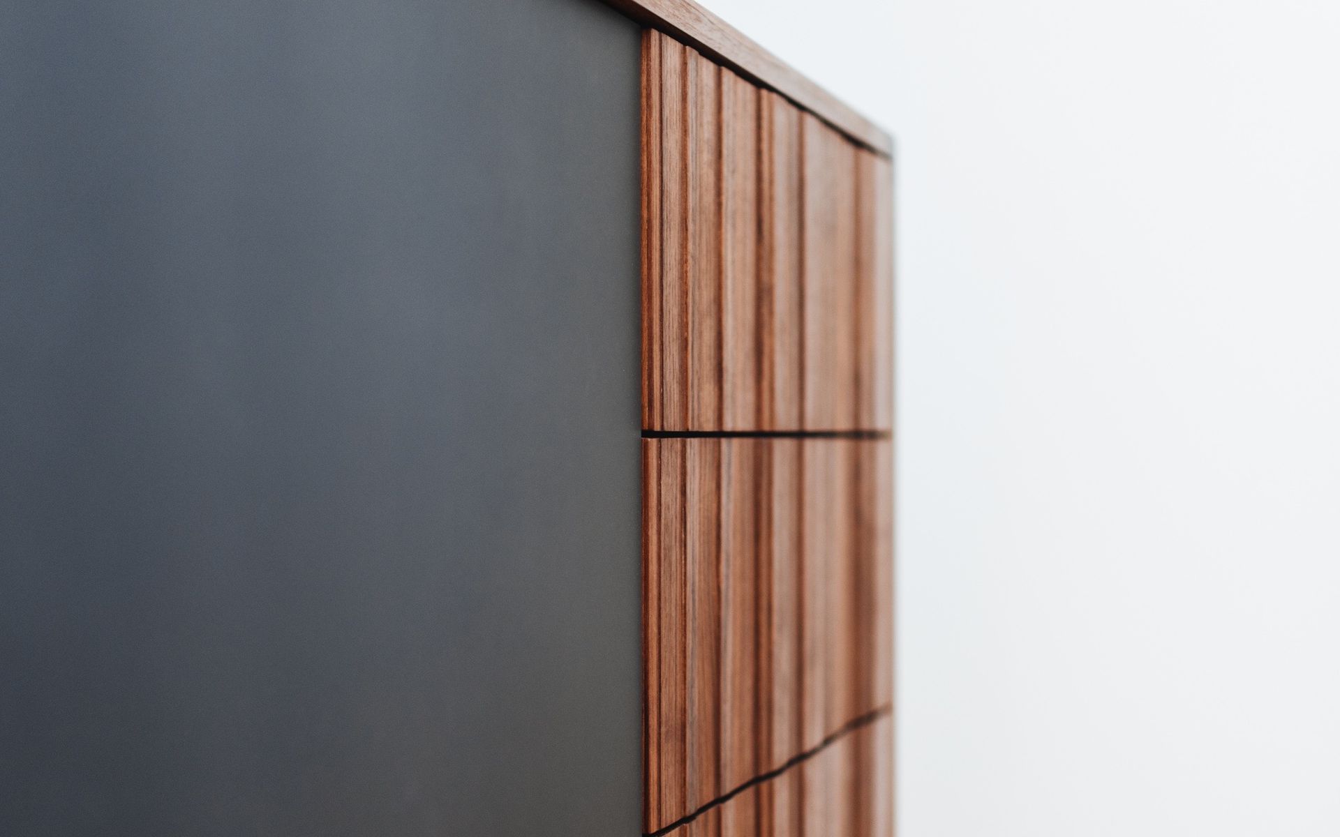 Detailaufnahme der Schubkästen eines Sideboards im Midcentury-Stil aus geöltem Nussbaum mit anthrazitgrauer HPL-Oberfläche.