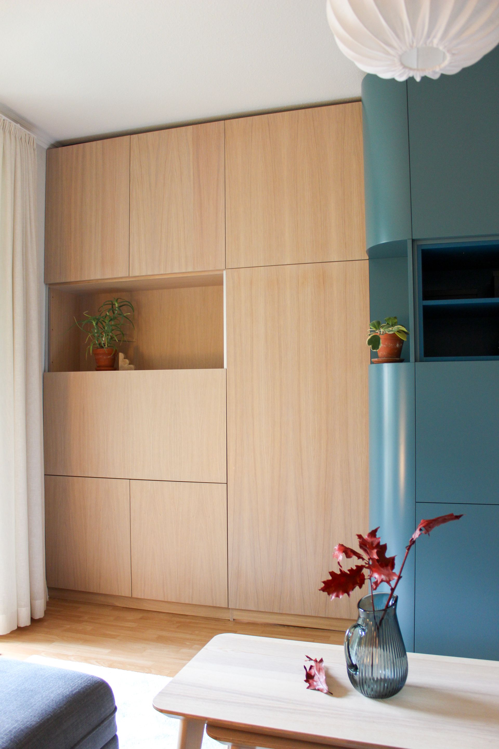 Raumtrenner raumhoch in Eiche und petrolfarbenen Oberflächen. TV-Fach verdeckt mit vertikalem Schiebetürbeschlag.