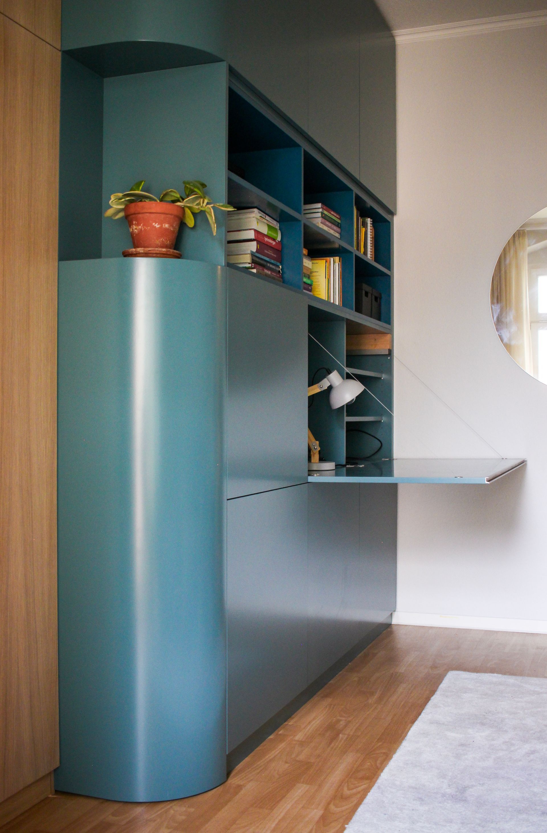 Raumtrenner raumhoch in Eiche und petrolfarbenen Oberflächen. Individuell angefertigte Runde Ecke. Bücherschrank.