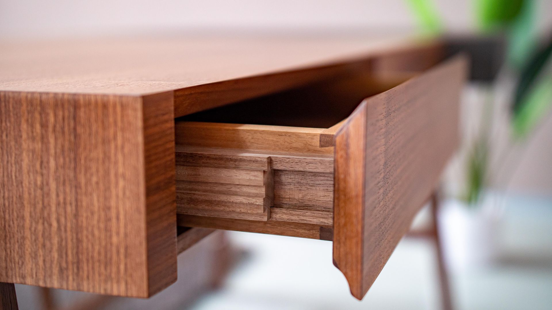 Detailaufnahme eines Schreibtisches in geöltem Nussbaum mit Massivholz-Kulissenauszug.