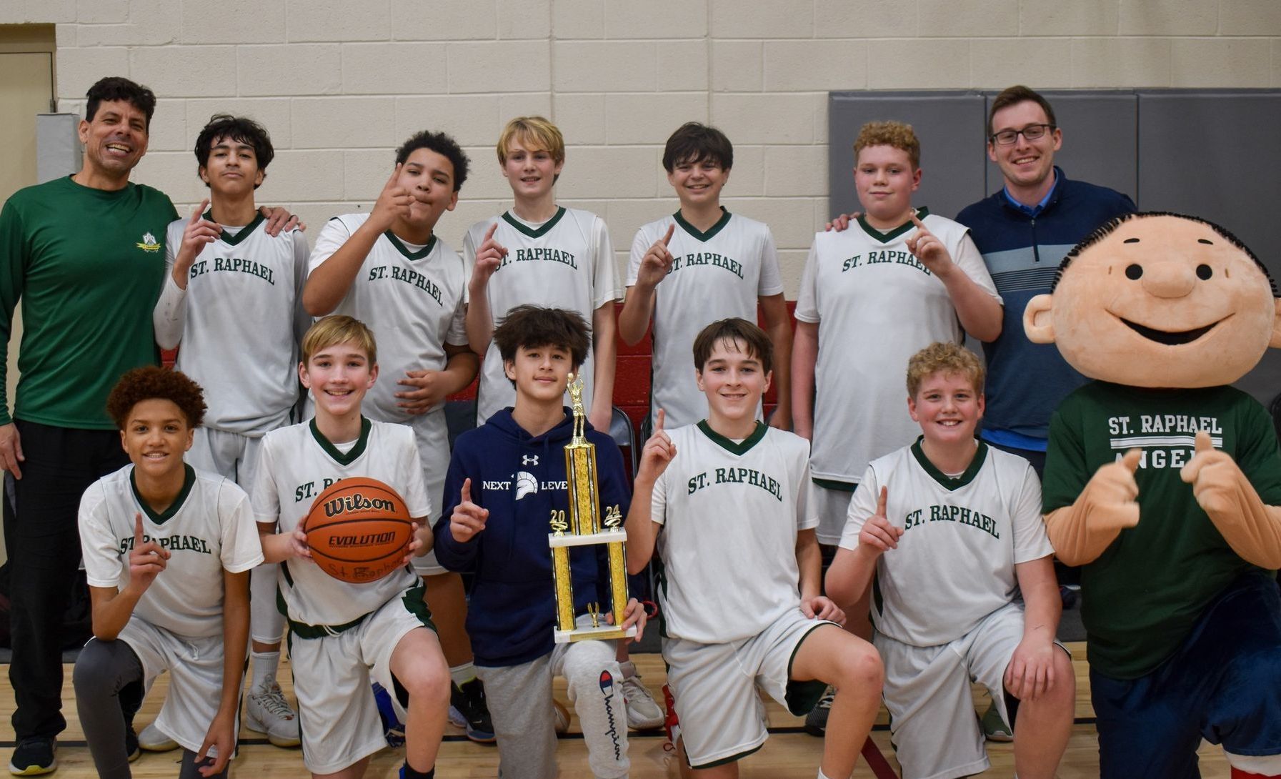 A boy wearing a green t. rafael jersey dribbles a basketball