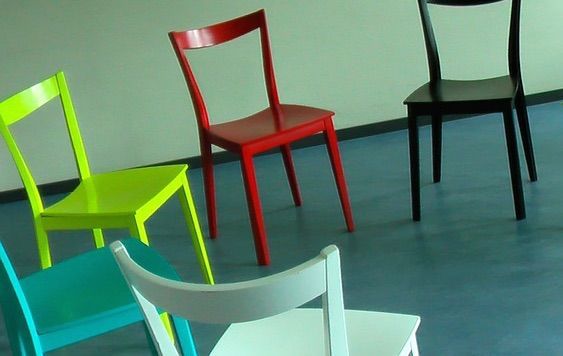 Four colorful chairs are lined up in a circle on a blue floor